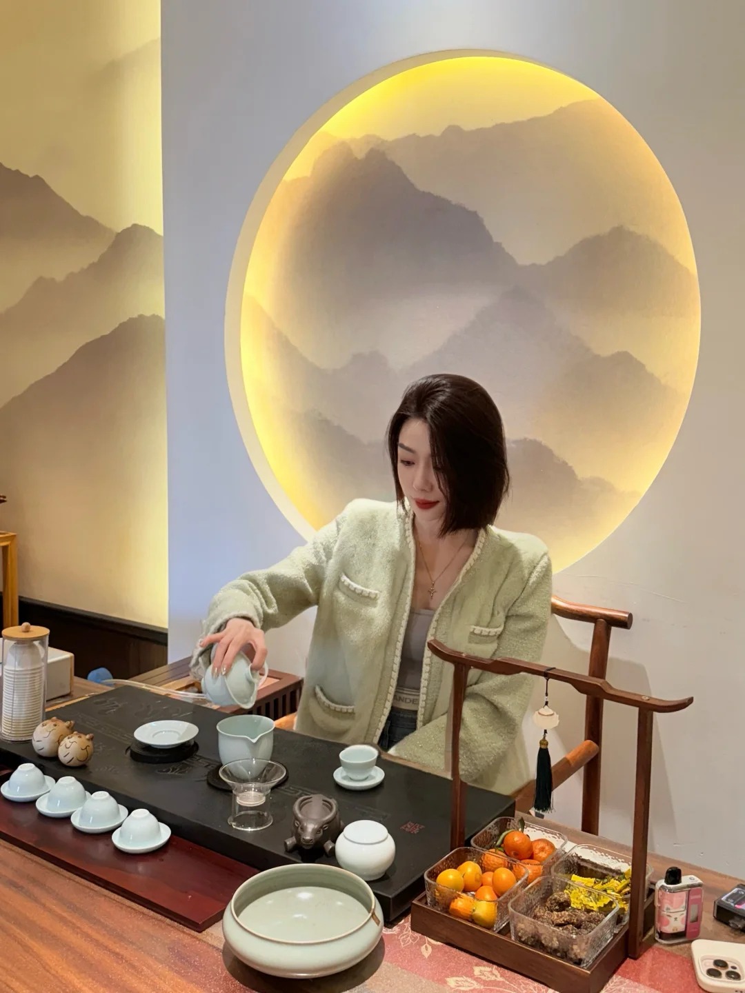 浅绿色衣着人物坐在圆形装饰灯前